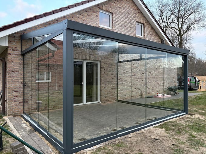 Kaltwintergarten aus Aluminium mit rahmenlosen Glasschiebewänden an einem Klinkerhaus in Sögel – Terravista Meppen